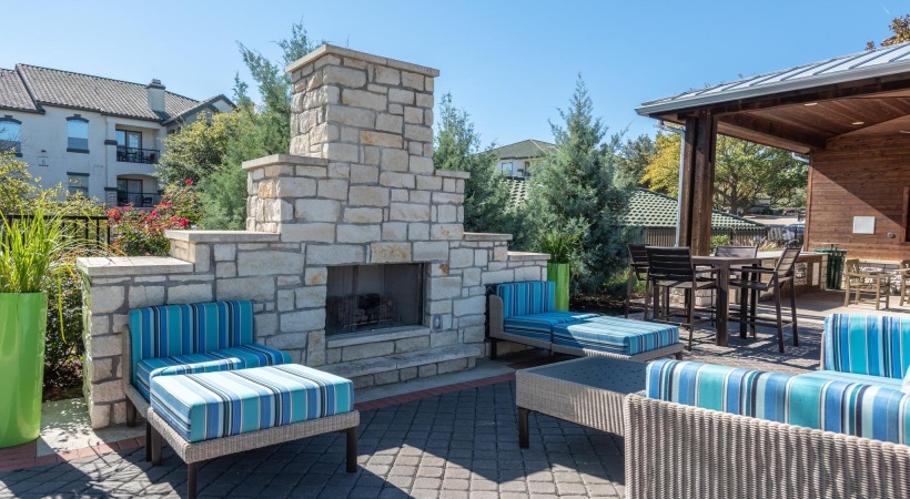 a patio with a fireplace and chairs